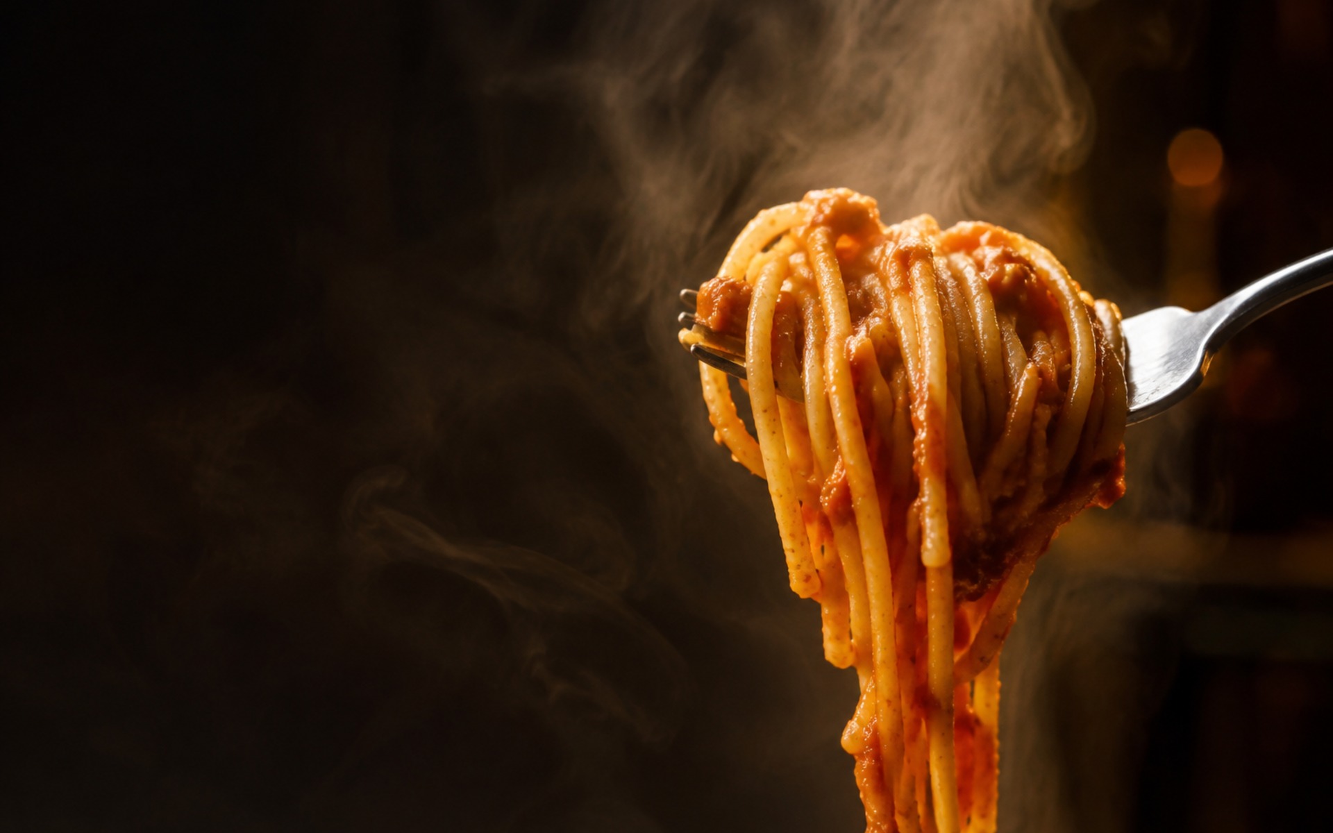 Gabel mit frisch gedrehter Spaghetti in Tomatensauce vor dunklem Rauchhintergrund